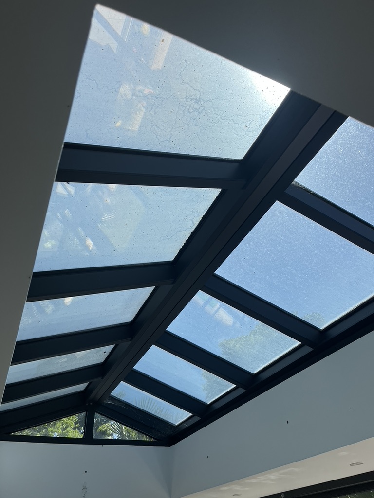 Verrière vue de l’intérieur avant nettoyage, avec des dépôts sur le vitrage.